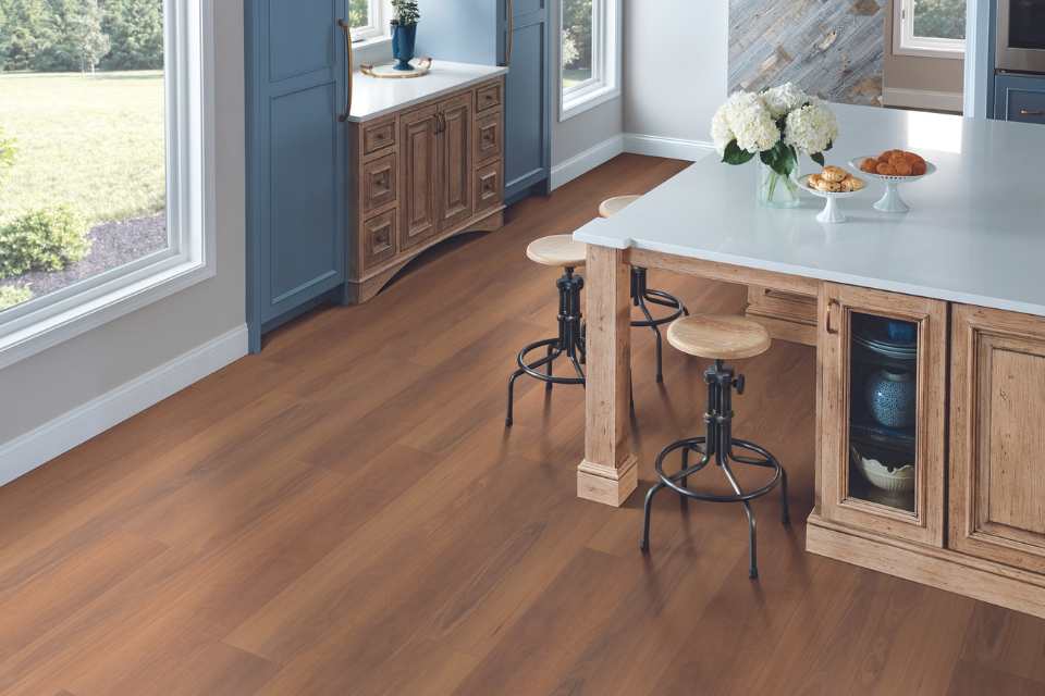 medium toned wood look luxury vinyl floors in modern kitchen with blue accent cabinets